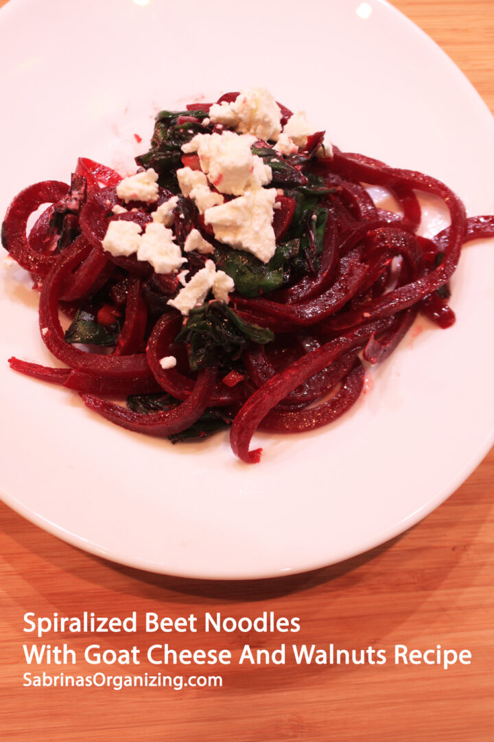 a white plate on a wood table - with the beet noodle dish on it. title of the post is at the bottom - pinterest image
