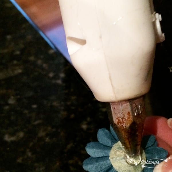 Use a hot glue gun and dab the back of the flower