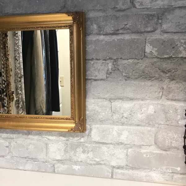 Self-adhesive wallpaper with bricks displayed on the wall in a walk in closet as a focal point. 