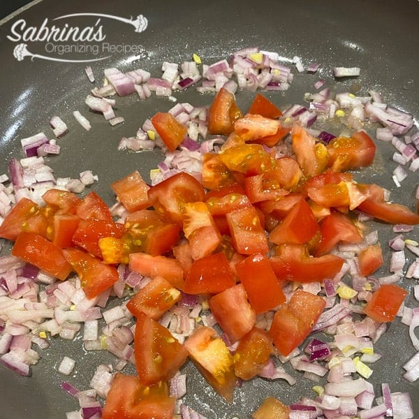 Tomatoes and onions cooking in skillet