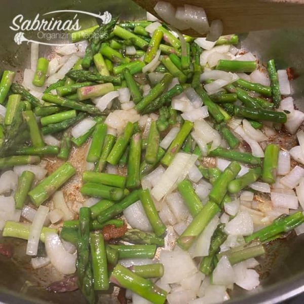 Cooked asparagus and onion in the deep sauce pan