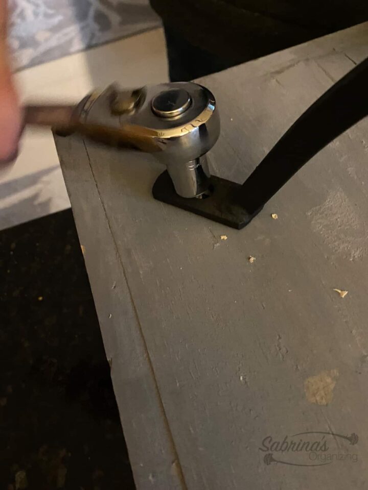 Use a wrench and add screw the legs to the tray