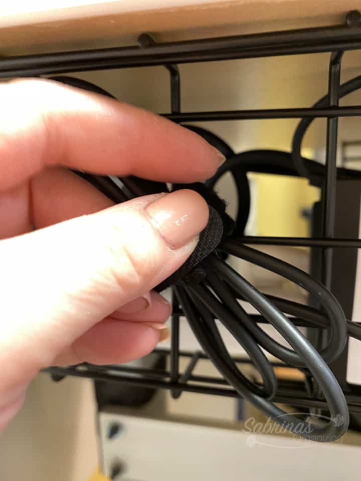 Wrap the cable around the hand and use a velcro strip to tighten it then use another velcro strip around the wire basket to hold it in place.