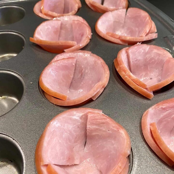 Add the cut Canadian Bacon to the muffin tray