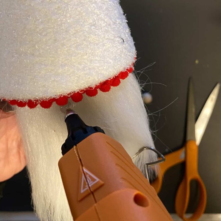 Add hot glue to glue the wooden nose on the beard.