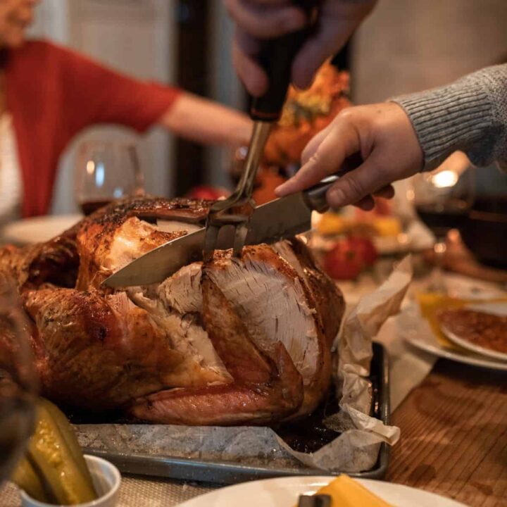 table with turkey on it and someone cutting it