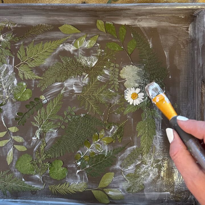 Add the Mod Podge then press the flowers on to the tray above the greenery