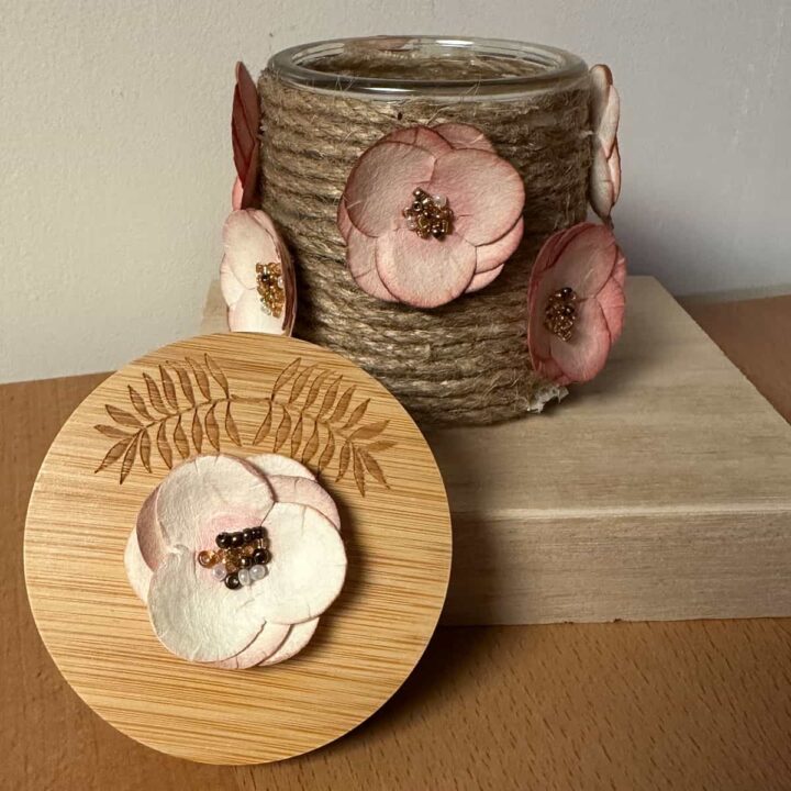 Finished jute oui jar with lid and flowers on it. no title on image - square
