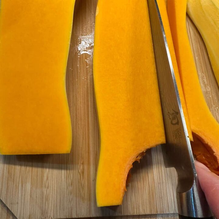 cutting a butternut squash long ways with a knife, square image