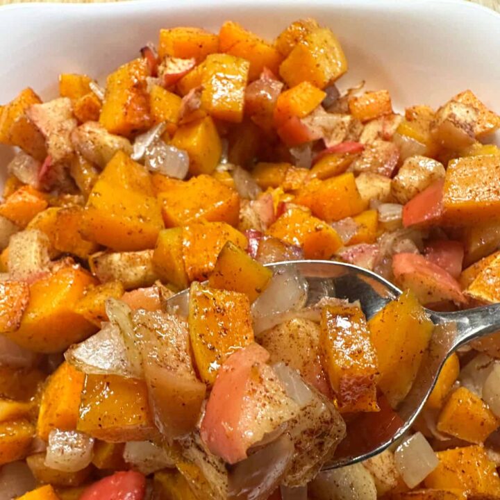 finished dish with a spoon of the cooked butternut squash apple and onion - square image