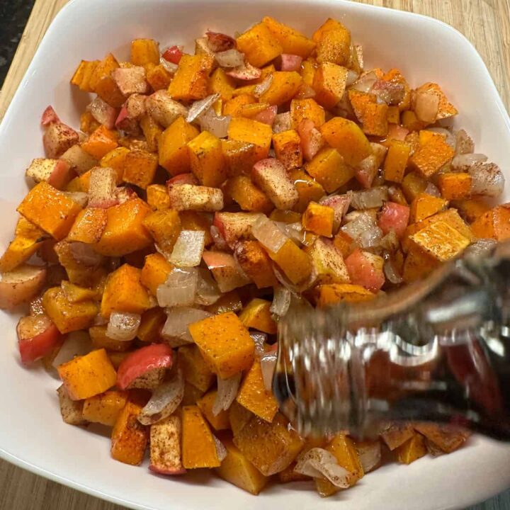 add maple syrup to the top of the bowl of cooked butternut squash, apple, and onion in a bowl - square image