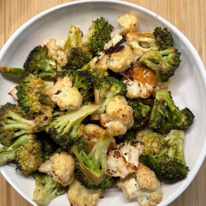 Broccoli and cauliflower in a bowl on a cutting board on pinterest size image with title of post at the top center