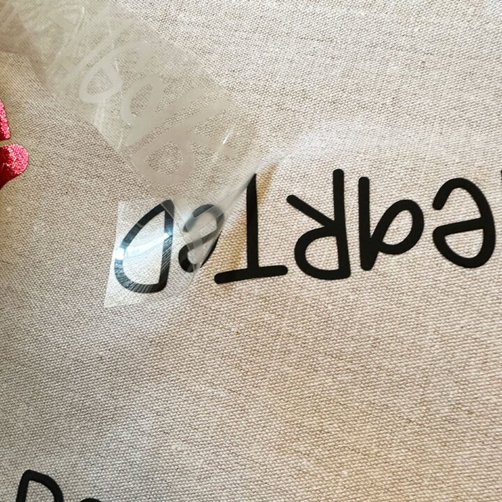 my hand peeling off the vinyl backing on a word on the runner - square image
