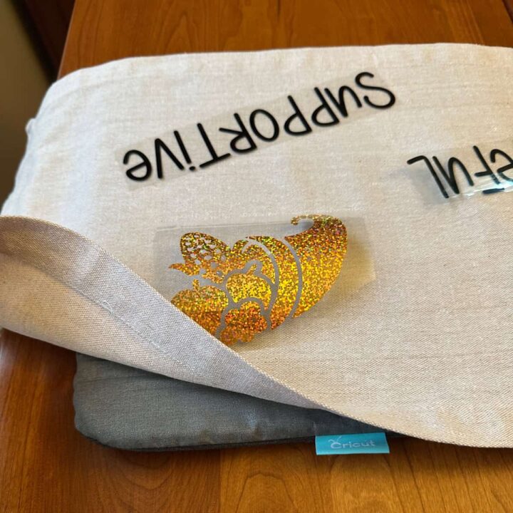 added the mat to the bottom of the runner to protect the table - word supportive and a cornucopia on top of the fabric with the backing still attached. - square image