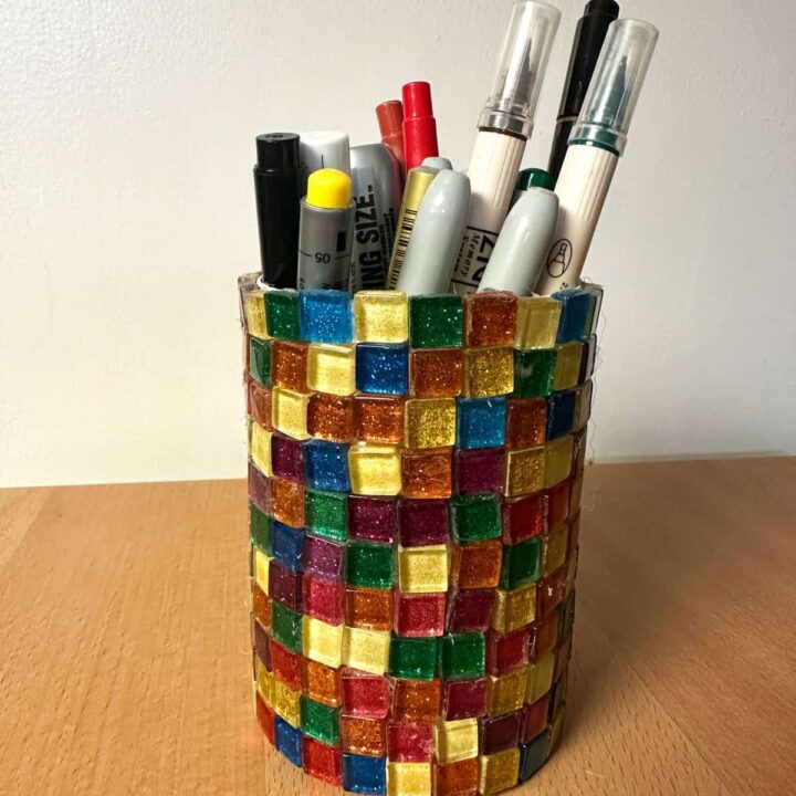 A picture of the tin can with the glass tiles around it with makers and pens in it - square image