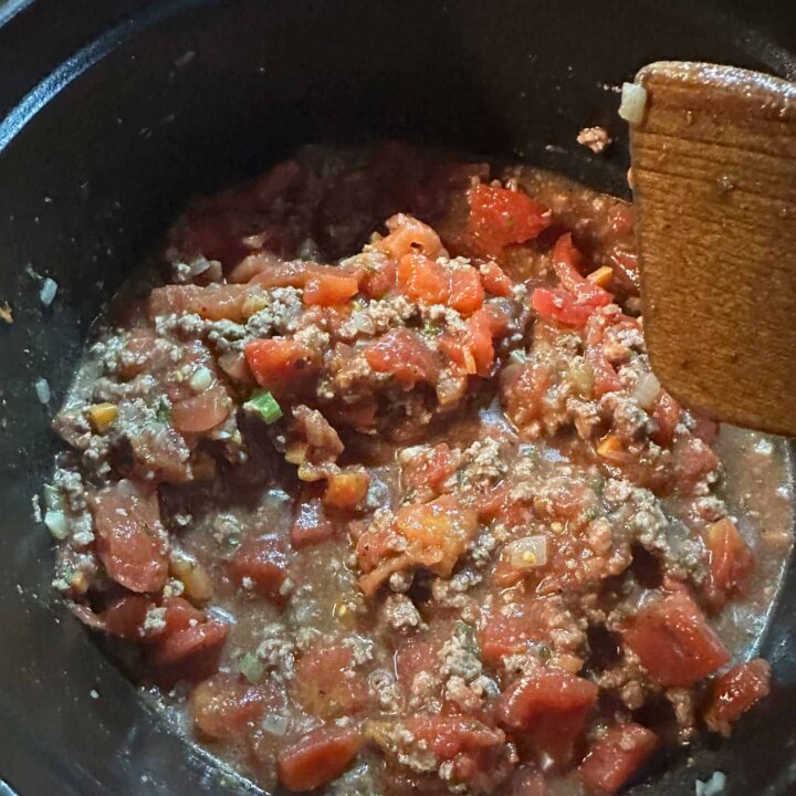 All the ingredients in the slow cooker and a wooden spoon - square image