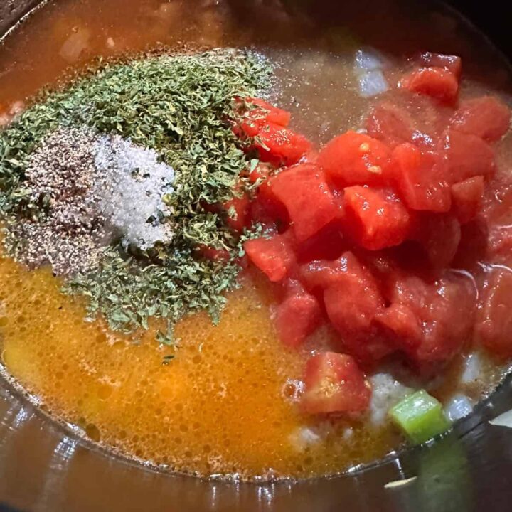 Tomatoes diced, herbs, and other things in a saucepan - square image