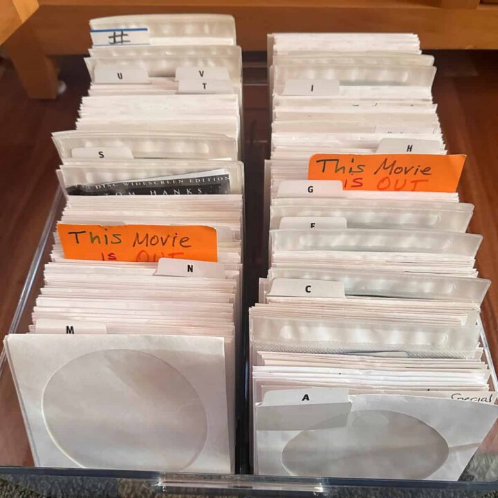 Bin with dvds in paper sleeves - square image - and index cards that are orange.