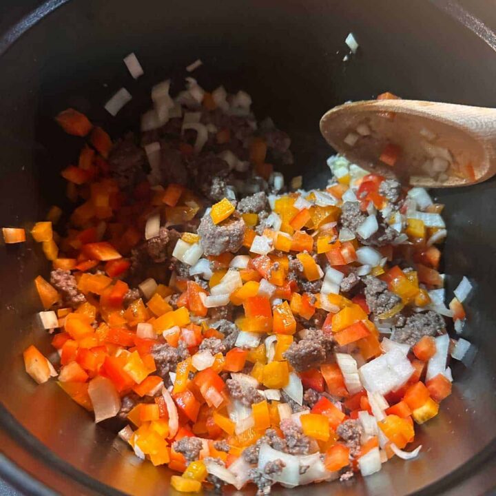 sauteed onions and peppers in a saucepan - square image